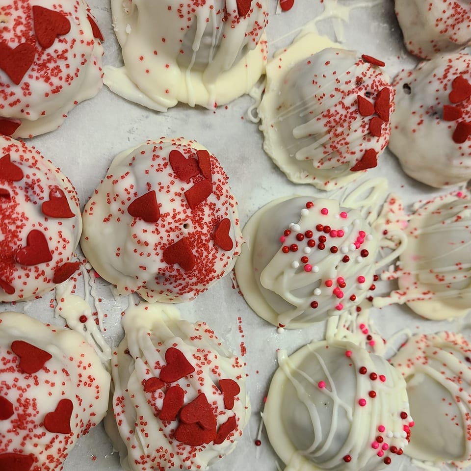 White chocolate-covered desserts with red heart sprinkles and pink and white round sprinkles.